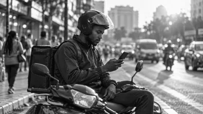 A courier on his parked scooter checking the next delivery on his phone